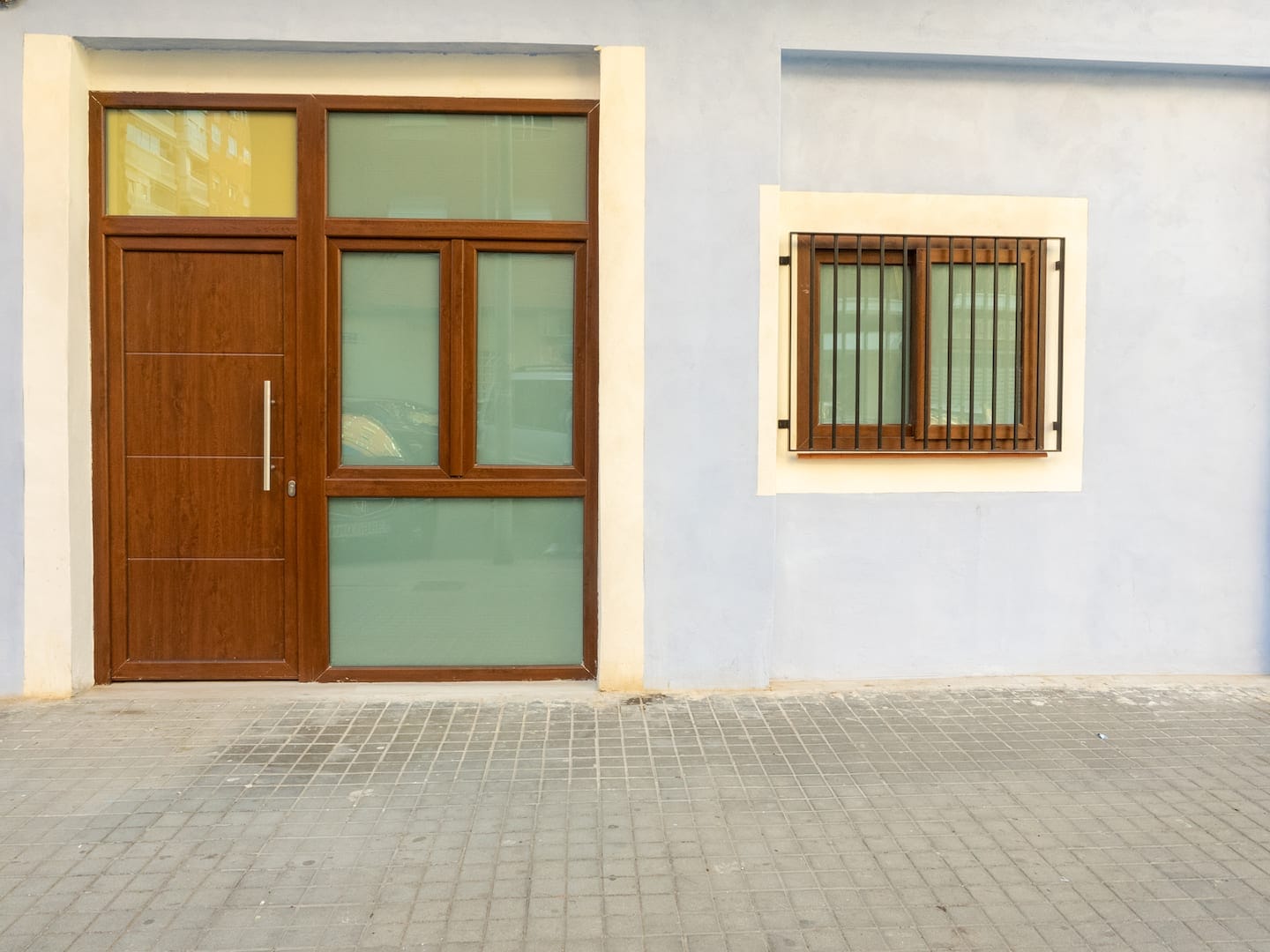 Fachada azul con puerta de madera y ventana enrejada