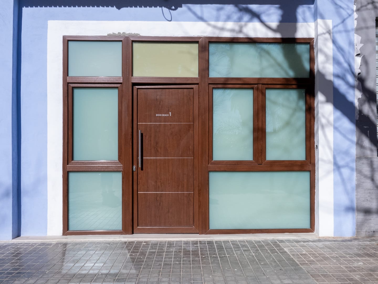 Puerta de madera de un estudio en la fachada azul